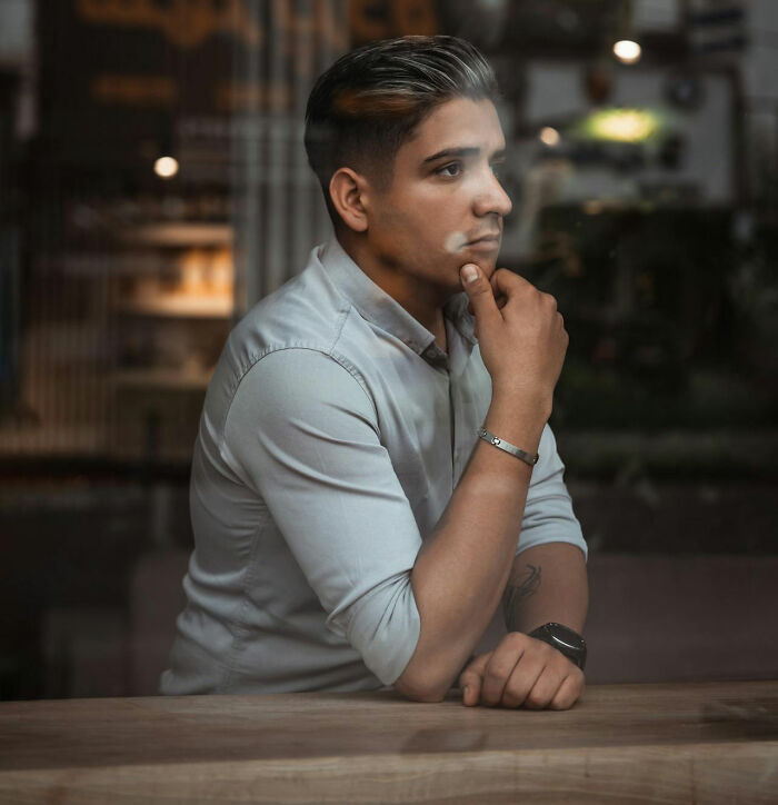 Man contemplating behind glass, reflecting on moving abroad permanently.