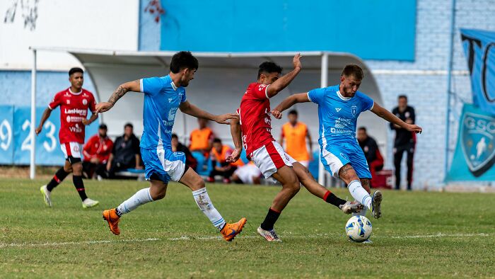 Soccer players in blue and red uniforms competing intensely on the field during a competitive match.