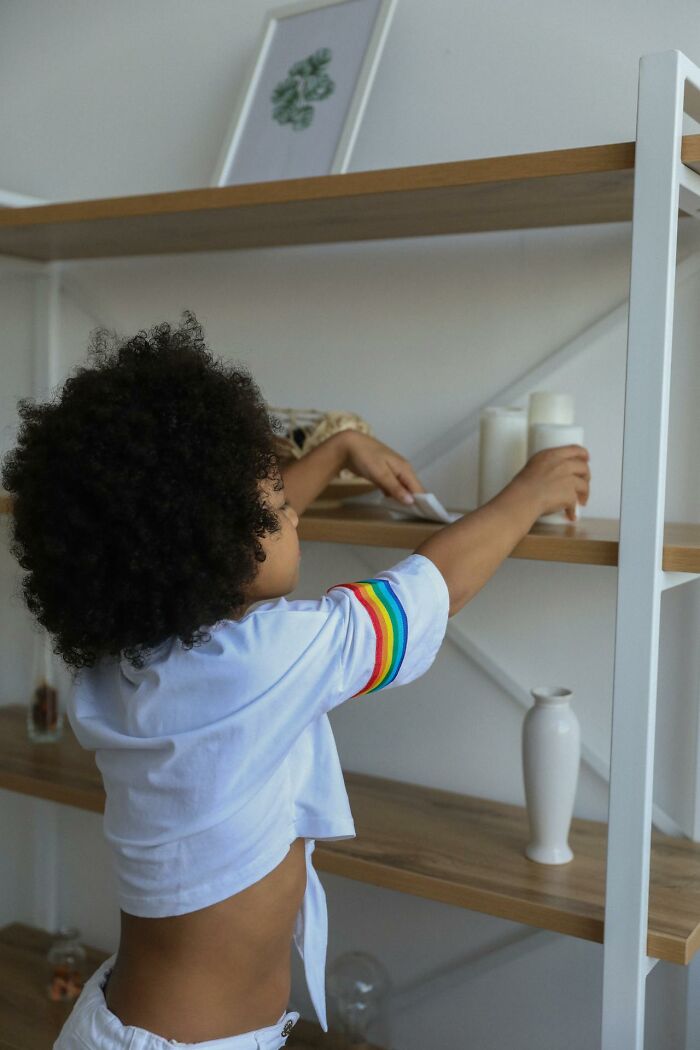 Child reaching for items on a shelf, showcasing unhinged mom sanity hacks.