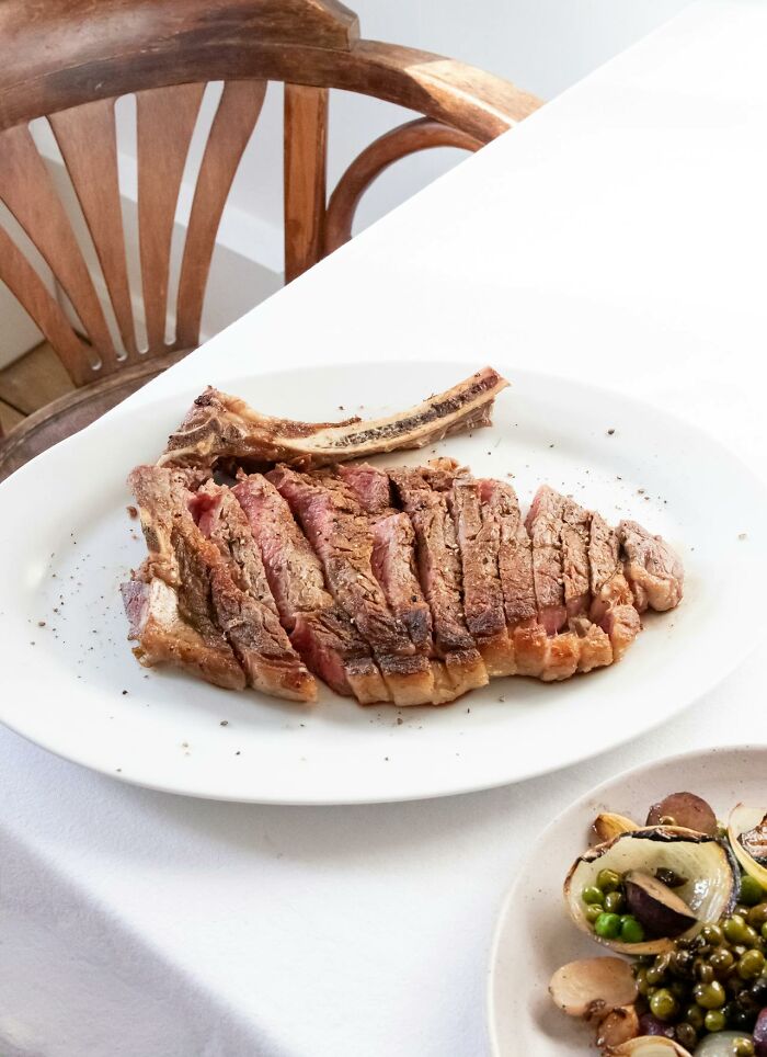 Sliced grilled steak on a plate with a side of mixed vegetables representing restaurant food items.