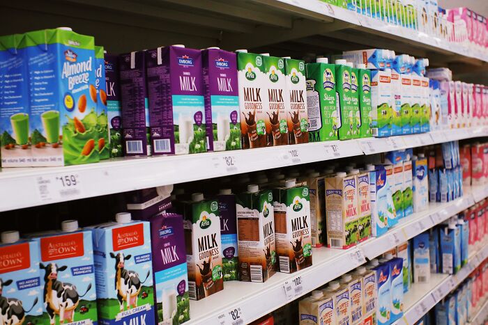 Supermarket milk aisle stocked with various brands and types of milk cartons.
