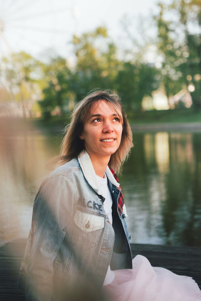 Young woman sitting by a lake, looking thoughtful and reflecting on obvious things just become aware of outdoors.