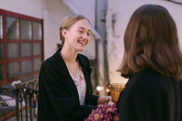 Two adults in conversation, one holding a bouquet, possibly discussing habits and maturity.
