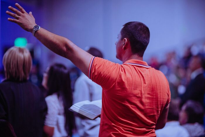 Person in orange shirt holding a book in a church setting, highlighting reasons to stop attending church.
