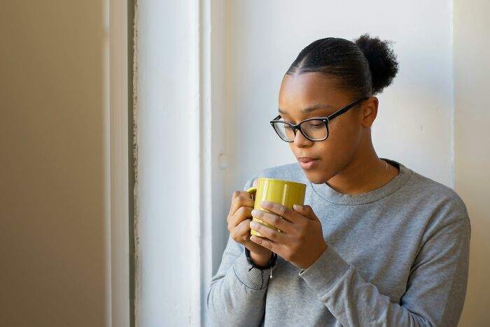 Young woman in glasses holding a mug thoughtfully reflecting on ghastly things told in church that made people quit going.