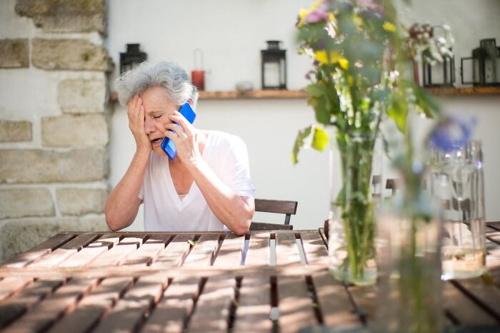 Elderly woman on phone looking distressed, illustrating an emotional first responder call experience.