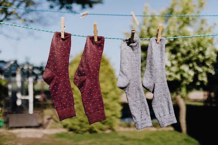 Socks drying on a clothesline in a garden, a simple mom sanity hack for organizing laundry.