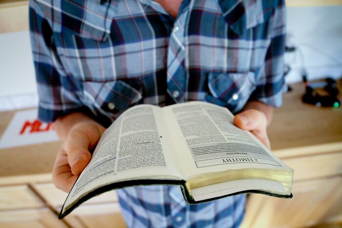 Person holding an open Bible, symbolizing reasons for not going to church.