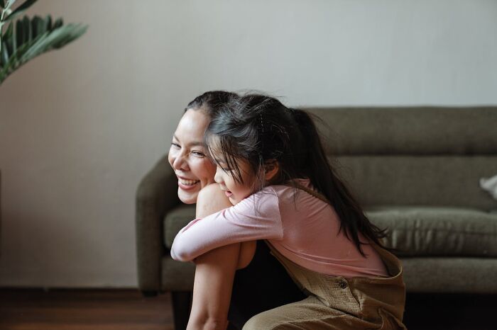 Mom and daughter sharing a joyful embrace on the couch, representing unhinged mom sanity moments.