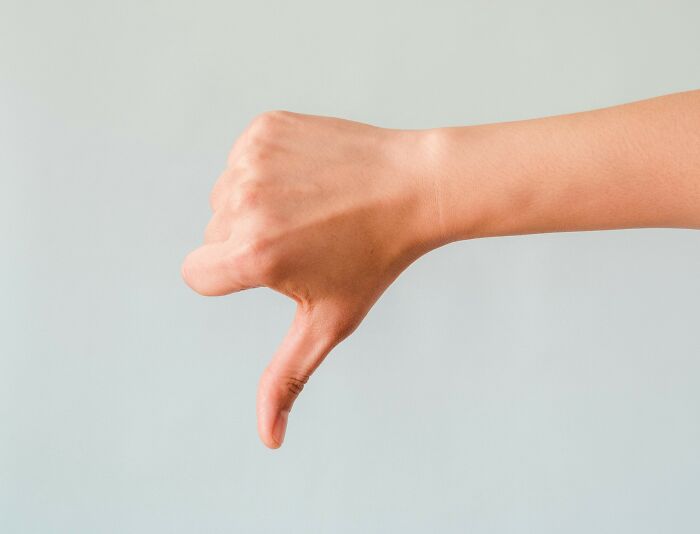 Close-up of a hand giving a thumbs down gesture symbolizing ladies share red pill stories and personal viewpoints.