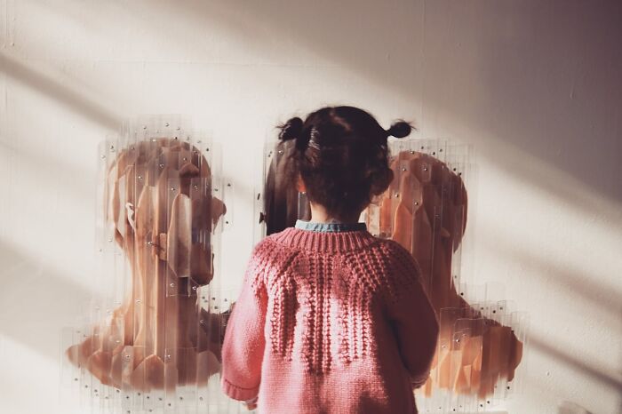 Child in a cozy sweater looking at a thought-provoking art piece, suggesting parental sanity hacks.