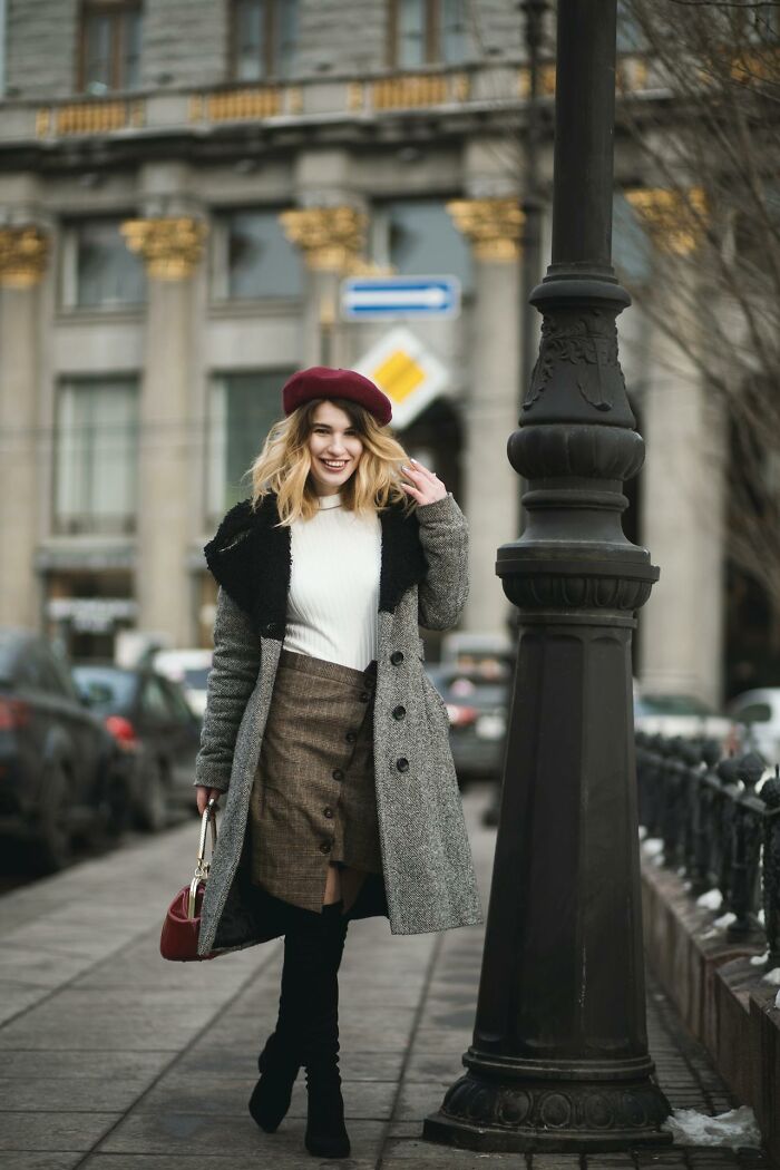 American abroad in stylish winter attire, strolling city street, smiling.