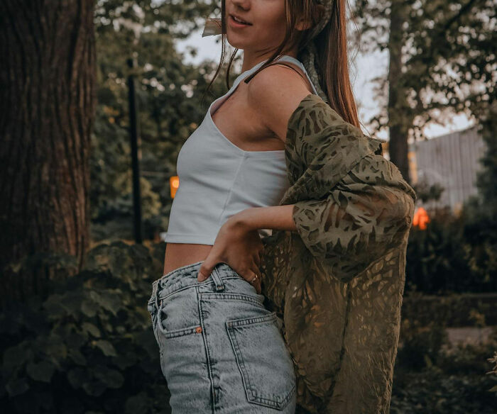 Woman standing outdoors in casual summer outfit, embodying confidence with a stylish pose amidst nature.