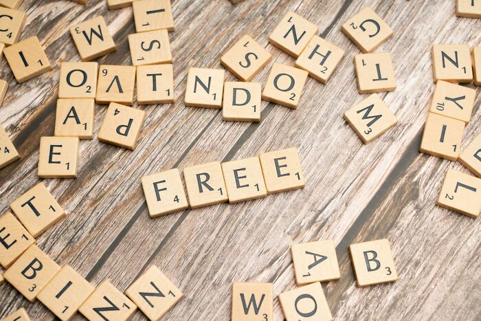 Scattered wooden letter tiles on a wooden surface with the word free spelled out, perfect for word puzzles and scrambles.