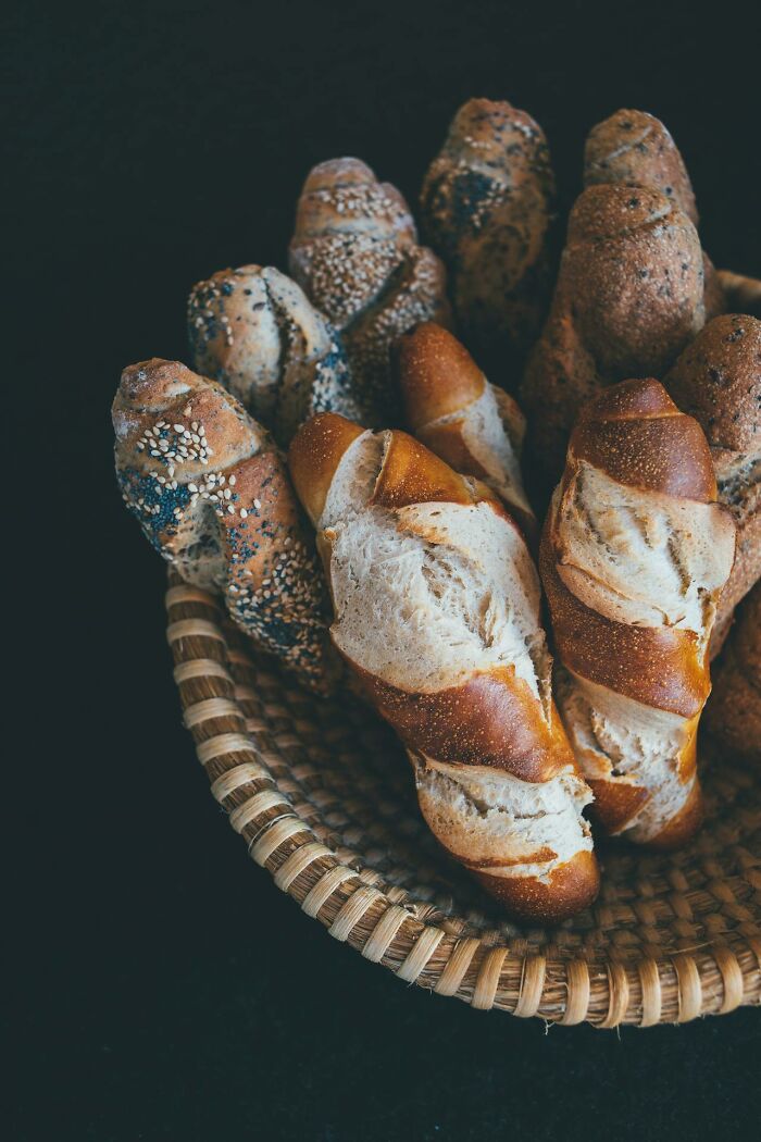 Basket of assorted fresh bread rolls with seeds, illustrating restaurant food items affected by price increases.