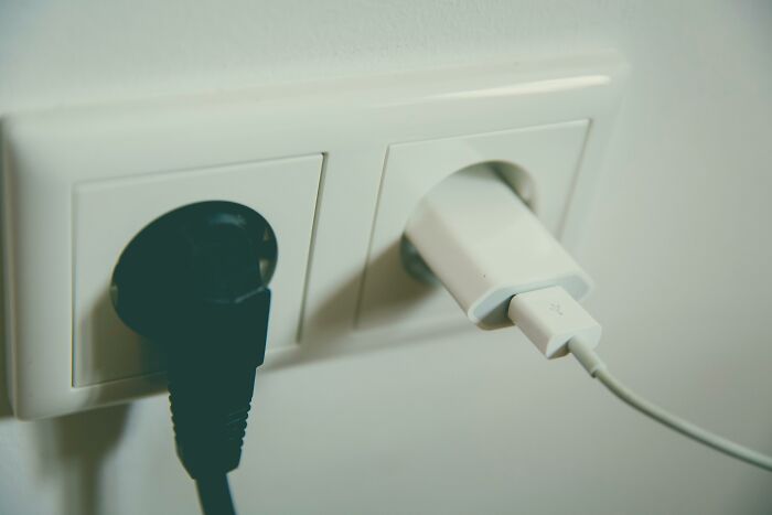 Two electrical plugs in a wall socket, representing a common intrusive thought about unplugging devices for safety.