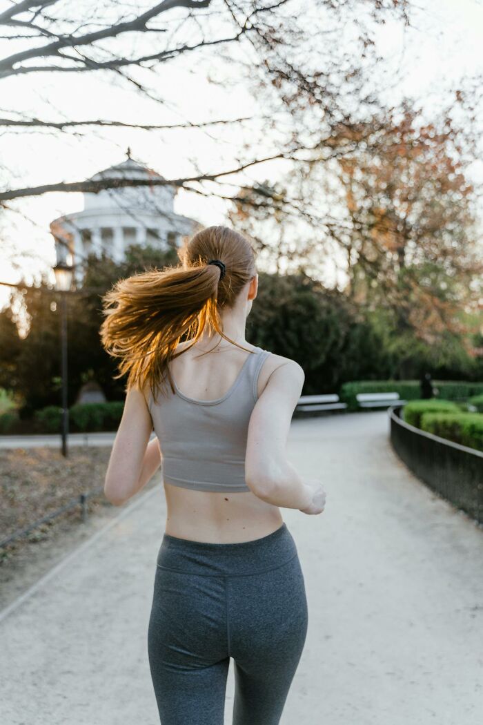Woman jogging in park at sunset, wearing workout clothes; relatable topics for women that confuse men.