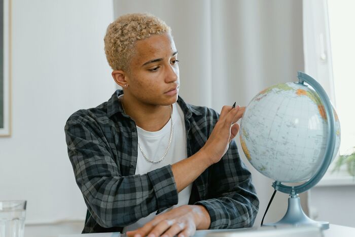 Person examining a globe, possibly identifying European capitals, in a contemplative setting. Person examining a globe, possibly identifying European capitals, in a contemplative setting.