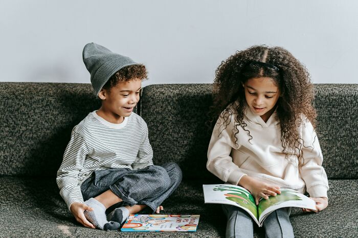 Two children sitting on a couch reading books, illustrating the theme of unexplainable pain.