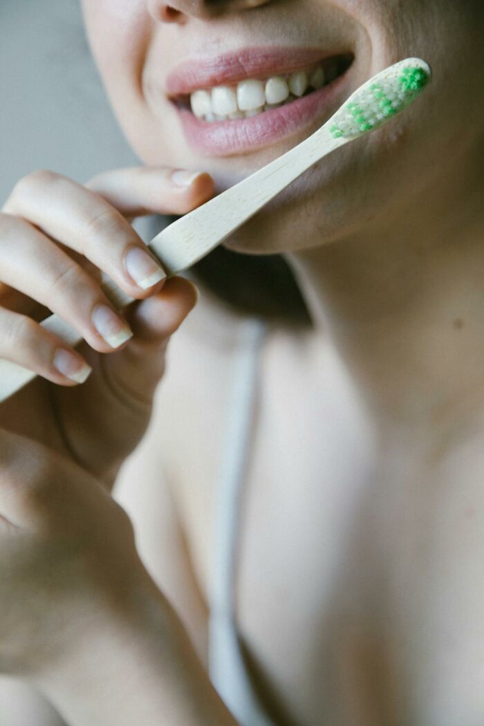 Person using a wooden toothbrush, illustrating personal cleaning rules and habits.