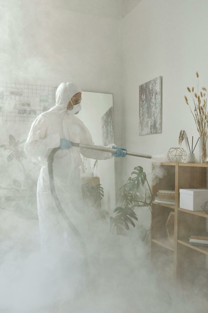 Person in hazmat suit fumigating a room, surrounded by mist, highlighting an unnoticed traumatic experience.
