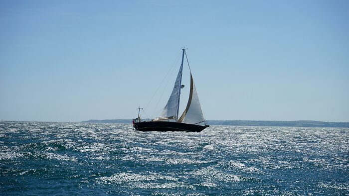Sailboat on choppy ocean waters under clear sky, representing fortunate moments after winning a lot of money in a lottery.