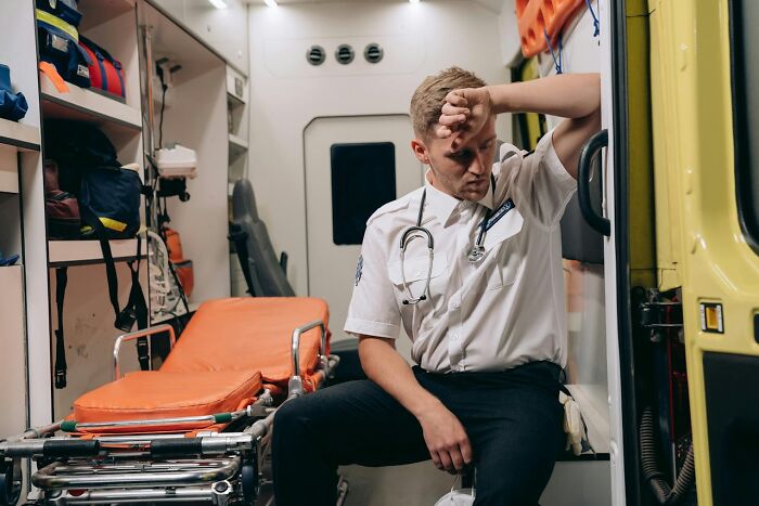 First responder in ambulance resting with hand on forehead, reflecting on a call they will remember for life.