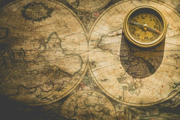 Vintage world map with an antique compass placed on top, symbolizing geography and global exploration quiz.