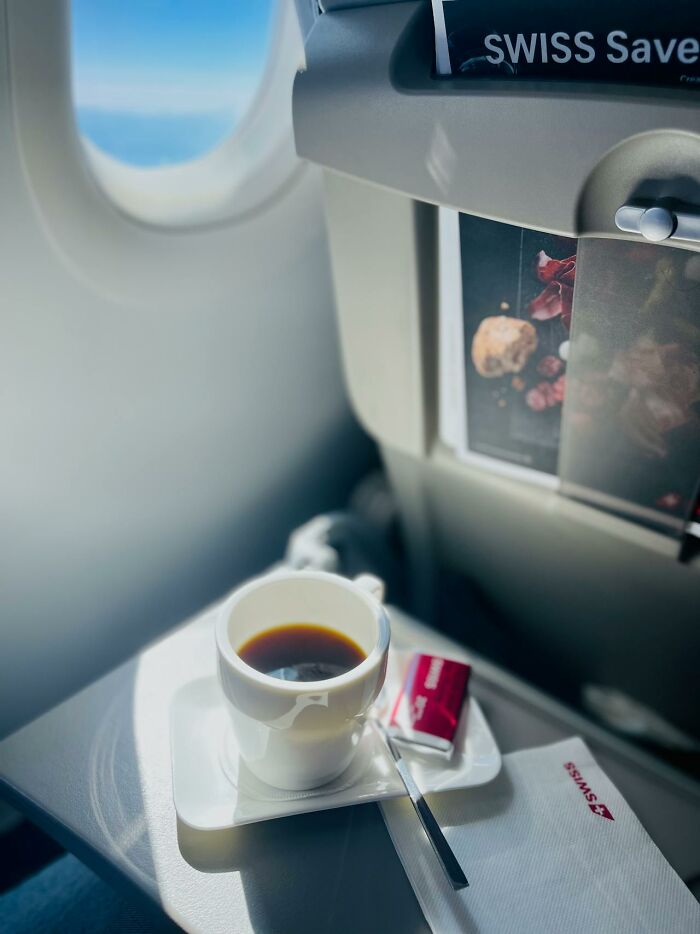 Cup of coffee on airplane tray table, window view, highlighting profession insights.