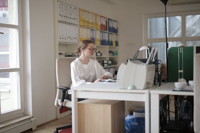 Woman working in an office, surrounded by binders, illustrating profession insights unknown to the general public.