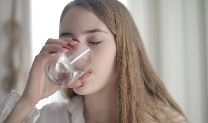 Woman drinking water to stay fresh, focusing on hygiene.