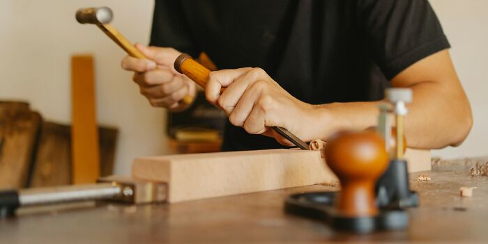 Person woodworking with a chisel and hammer, highlighting everyday things that can be dangerous.