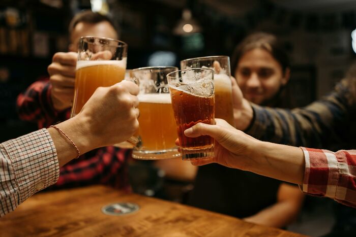 People clinking beer mugs in a bar, celebrating with drinks.