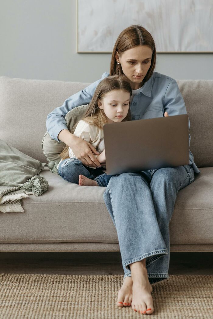 Mom and child sharing a laptop on a cozy couch, embodying parenting hacks and multitasking.