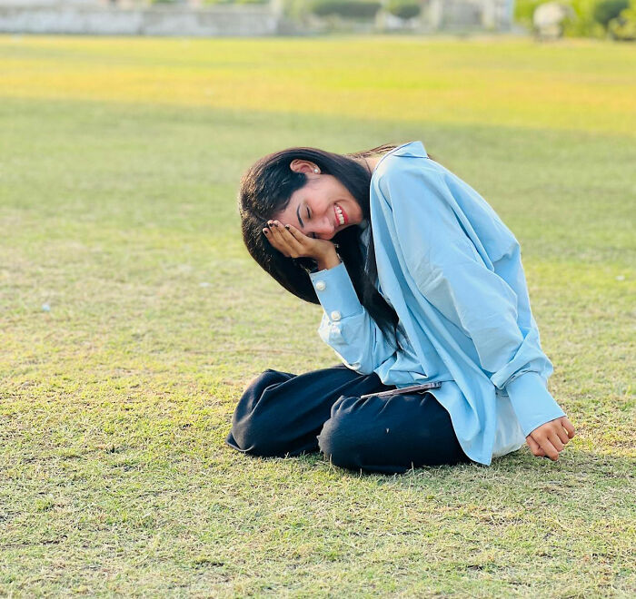 Young woman sitting on the grass with a smile, embodying the feeling of obvious things you've just become aware of.