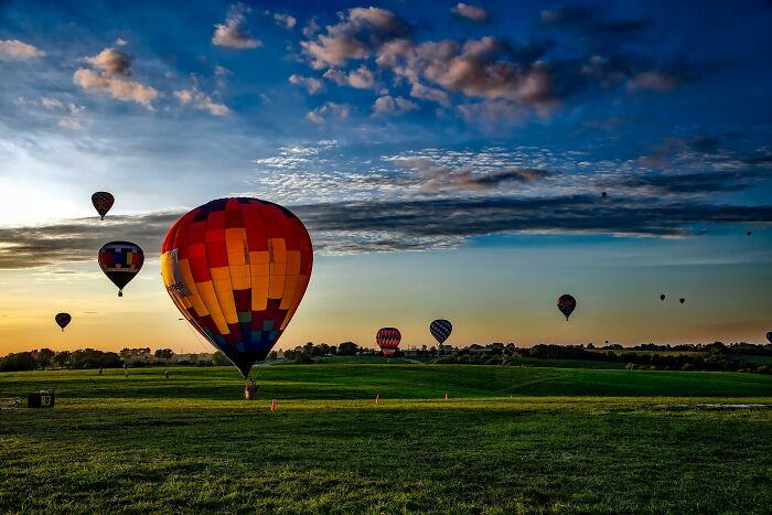 Colorful hot air balloons rising over a green field at sunset, symbolizing freedom from ghastly church experiences.