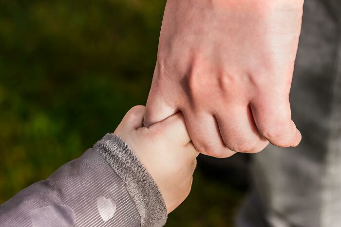 A child holding an adult's hand, symbolizing support in discussing reasons for not attending church.