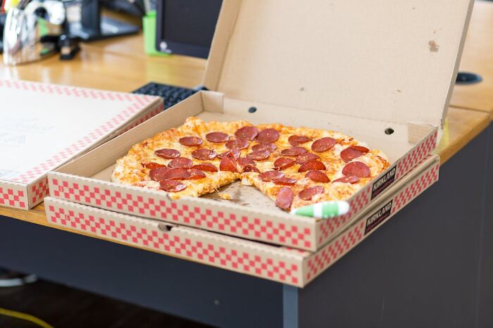 Pepperoni pizza in open cardboard boxes on a desk, illustrating popular restaurant food affected by price increases.