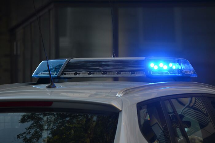 Police car with blue flashing lights at night, illustrating unlucky events for lottery big money winners.