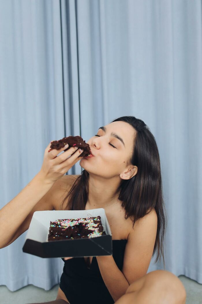 Woman enjoying chocolate cake with sprinkles, highlighting an overlooked aspect of profession in public perception.