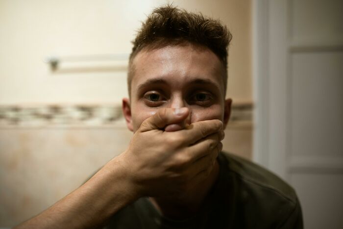 Man covering his mouth, reflecting stories from viral online thread on leaving church.
