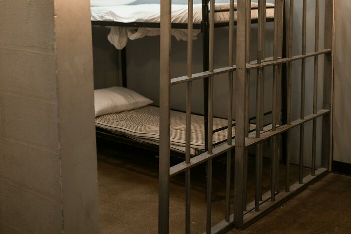 Empty prison cell with bunk beds and striped bedding, representing immature adult consequences.