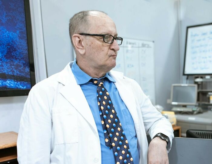 Doctor in white coat and glasses looking away, symbolizing unfair treatment from doctors in medical settings.