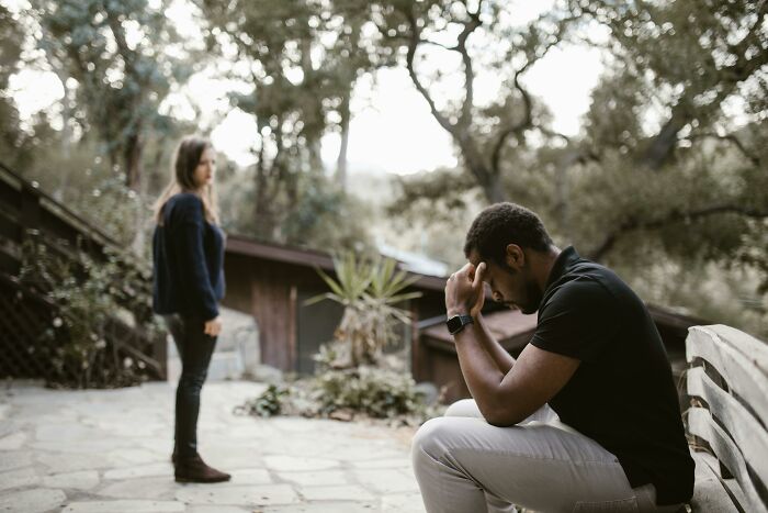 Two people in outdoor setting, one sitting pensively on bench, reflecting on reasons for not going to church.