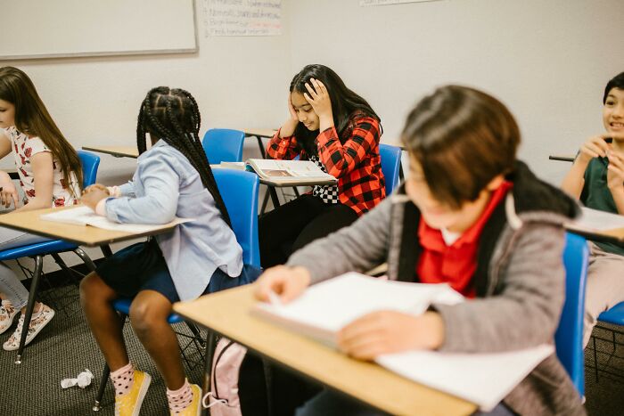 Students at desks in a classroom, with one appearing deep in thought, representing intrusive thoughts in learning environments.