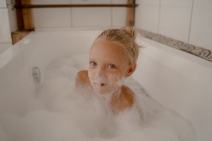 Child in a bathtub filled with bubbles, showcasing a playful moment.