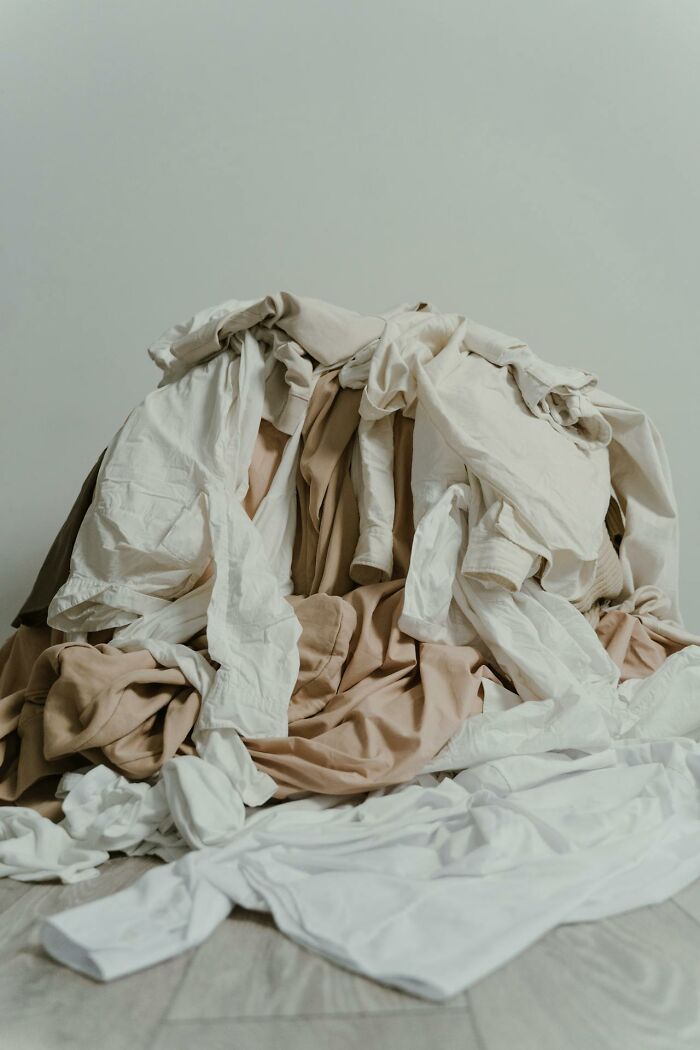 A pile of beige and white clothes randomly scattered, creating a creepy and cluttered effect in the room.