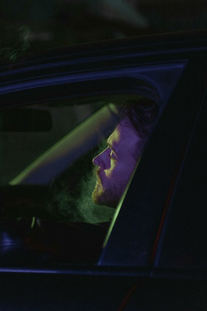 Person in a car at night with green light, hinting at professional insights unknown to the public.