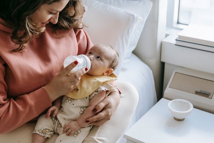 Mother feeding baby with bottle in a cozy room, reflecting obvious things just become aware of moment.