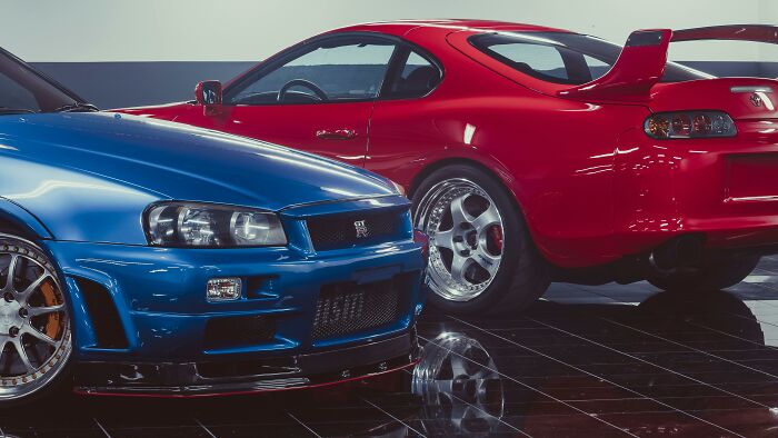 Two luxury sports cars, a blue and a red model, reflecting high-end purchases by lottery money winners.